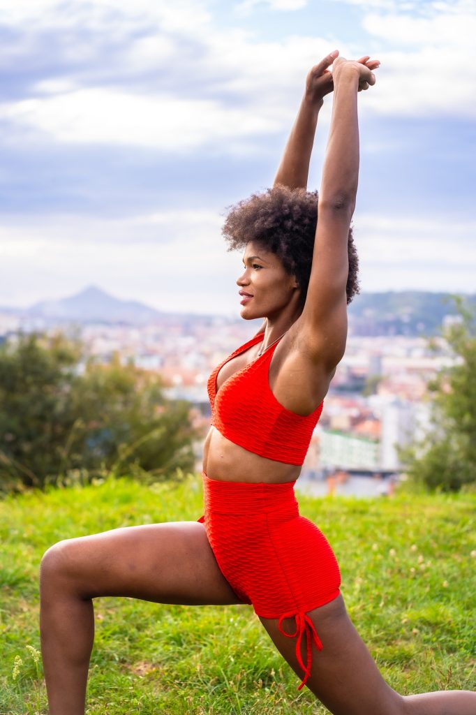 Fitness with a young black girl with afro hair, showing muscle, exercising in the field